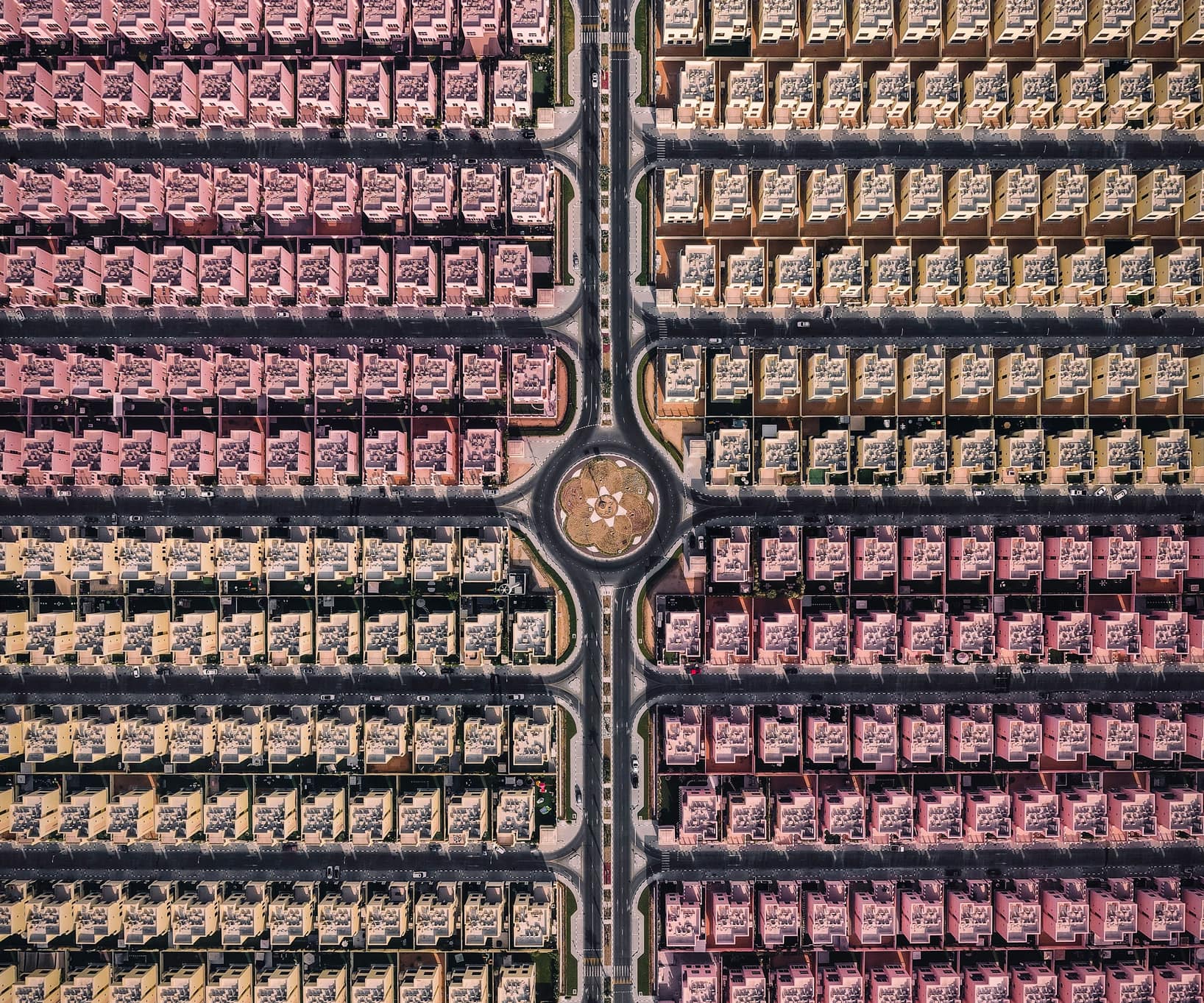 Aerial view of rows of colourful townhouses around a roundabout in a Dubai community
