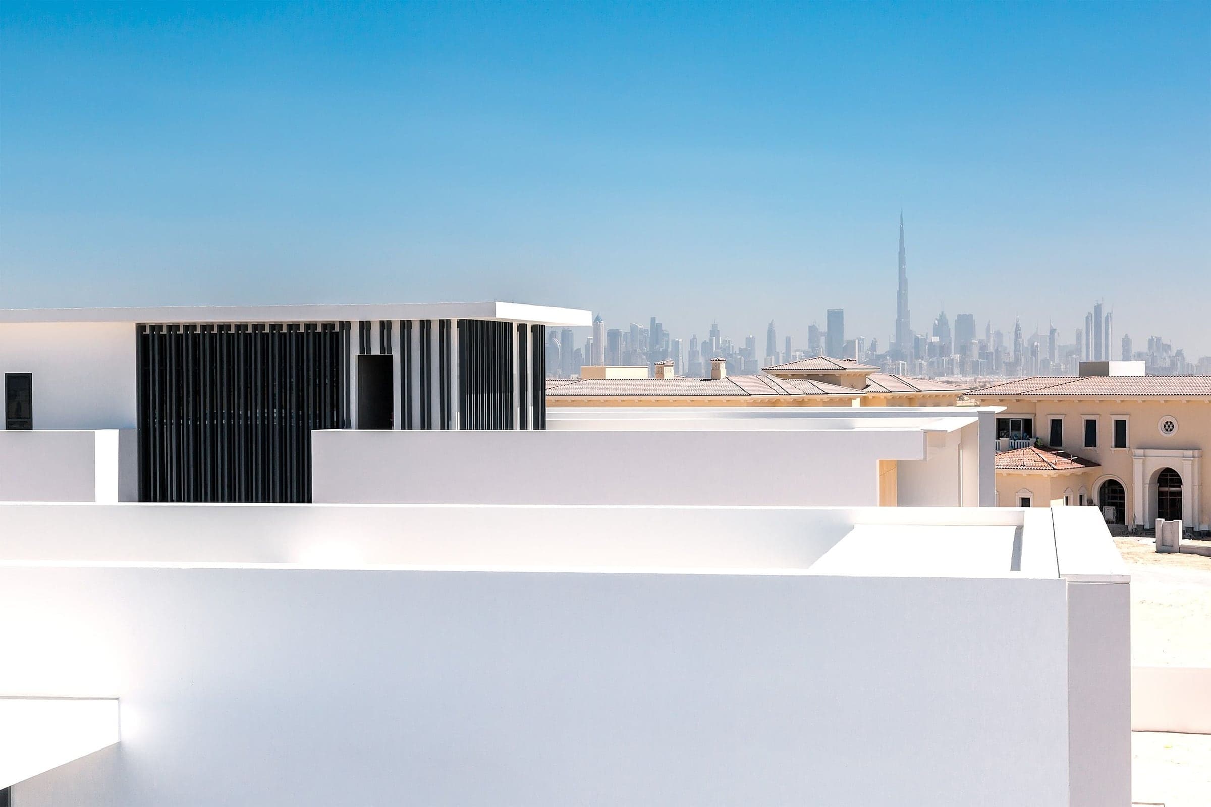 Contemporary white villa architecture with the Burj Khalifa and Dubai skyline on the horizon