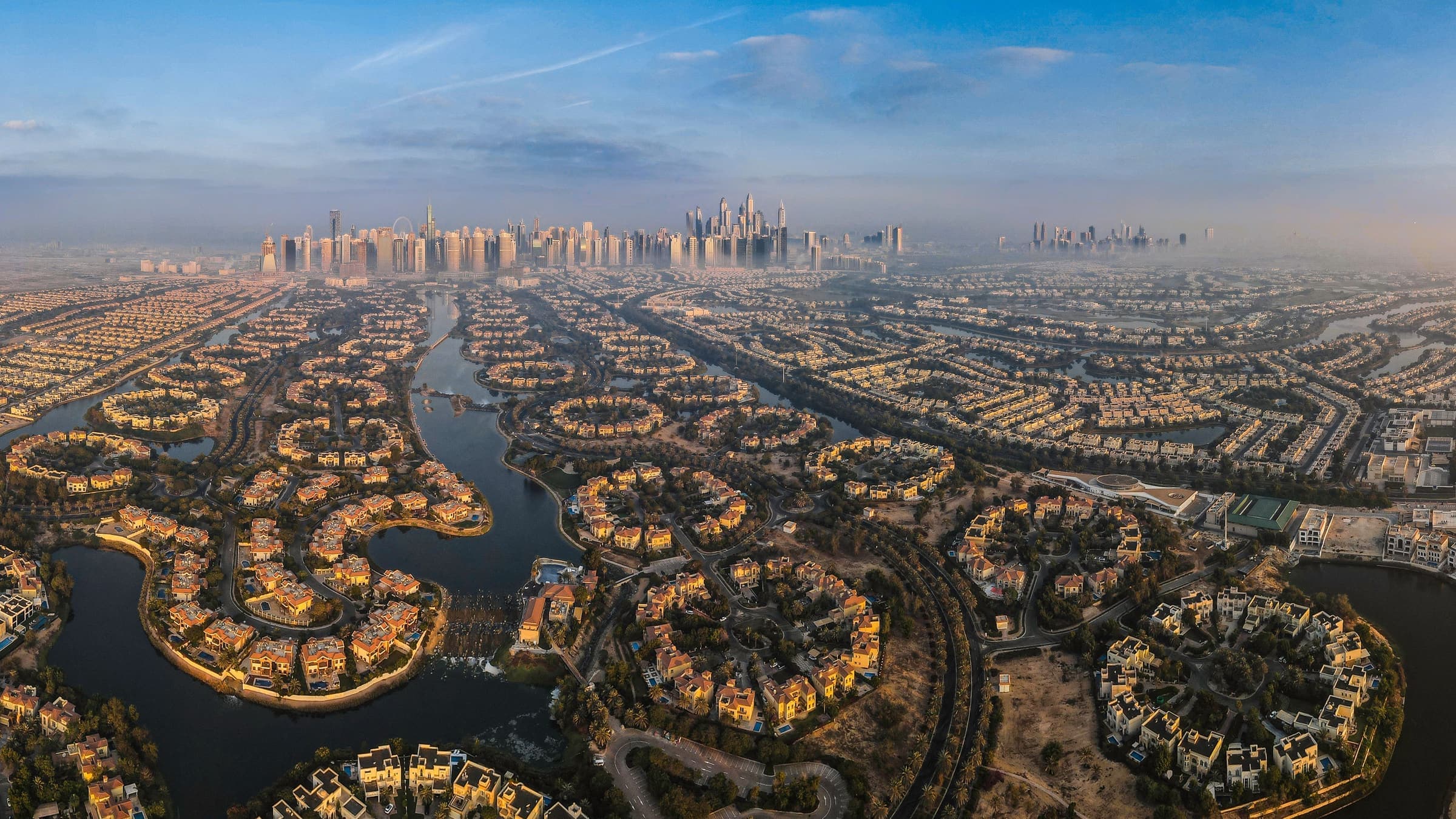 Aerial view of the Jumeirah Islands villa clusters set in their lakes, with the Dubai Marina and JLT skyline beyond