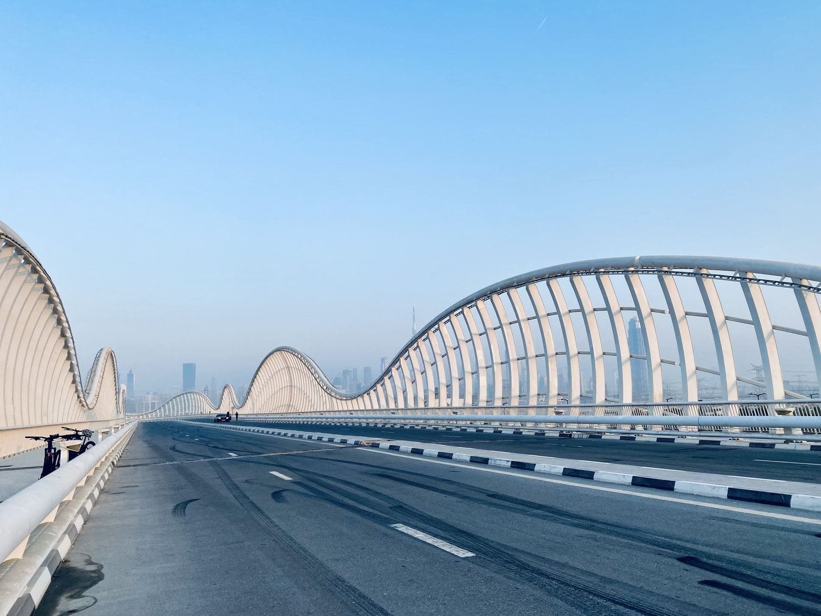 The wave shaped arches of the Meydan Bridge in Meydan, Dubai, under a clear blue sky