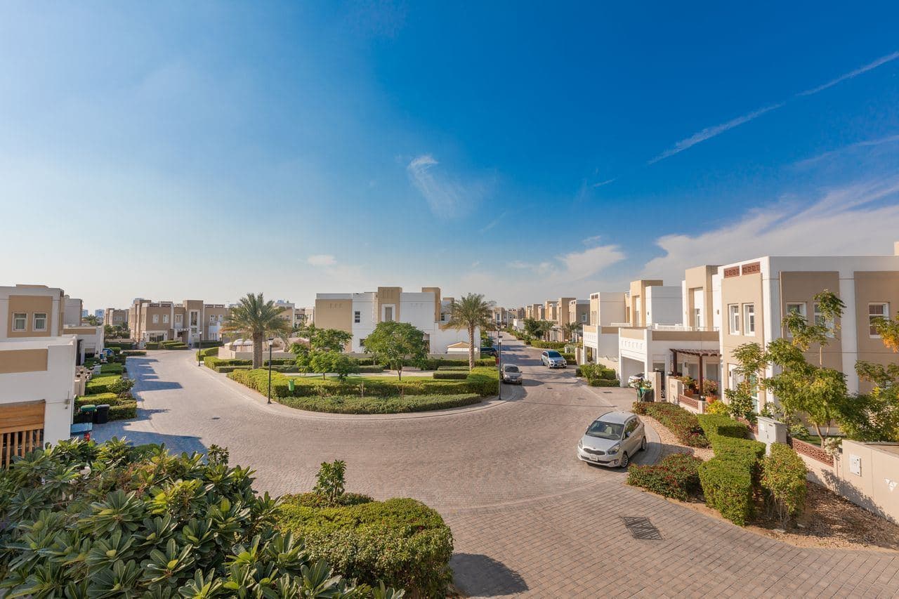 Townhouses, palm trees and a landscaped roundabout in the Mudon community, Dubai