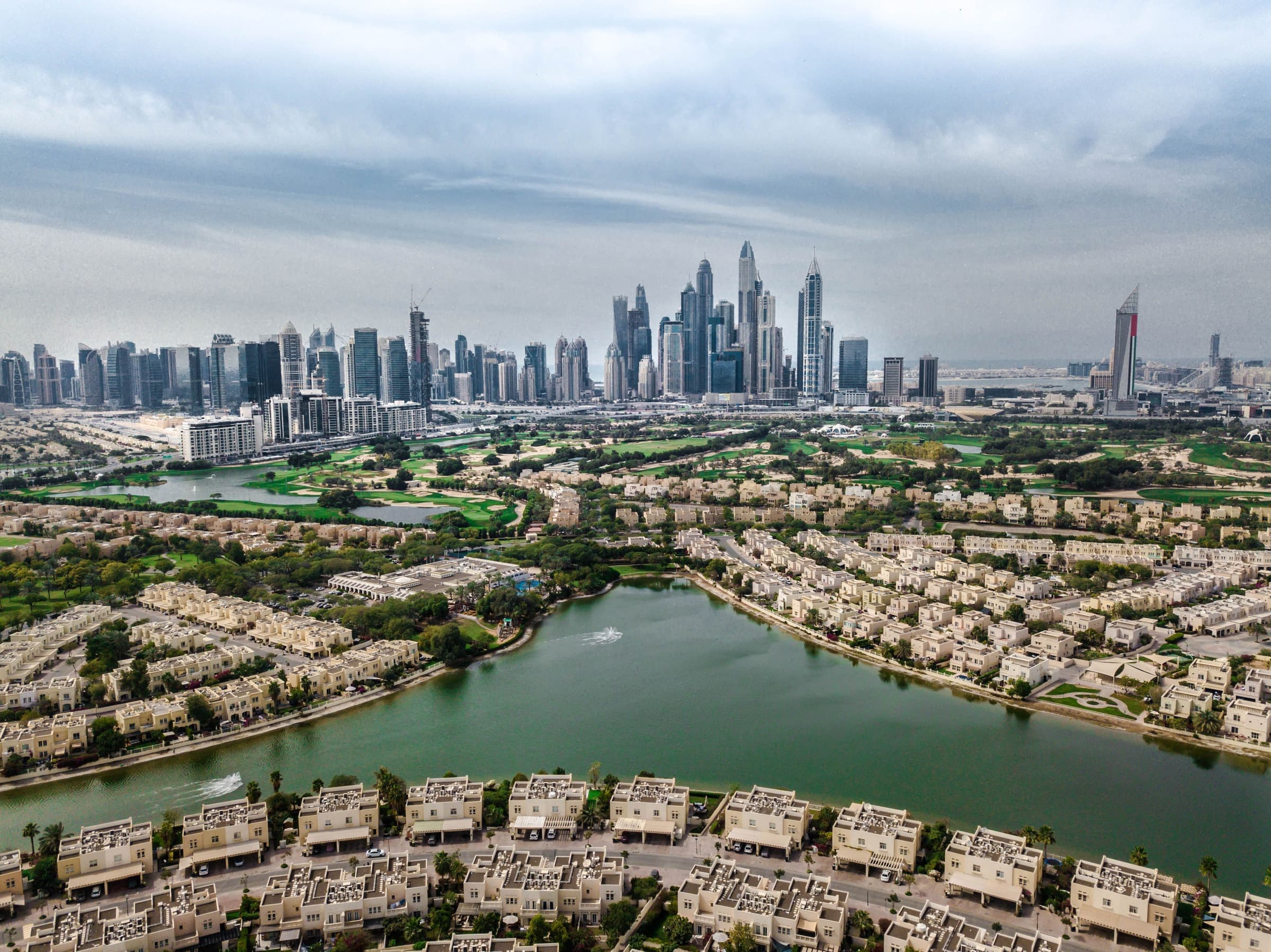 Townhouses of The Springs around a lake, with the JLT and Dubai Marina skyline beyond