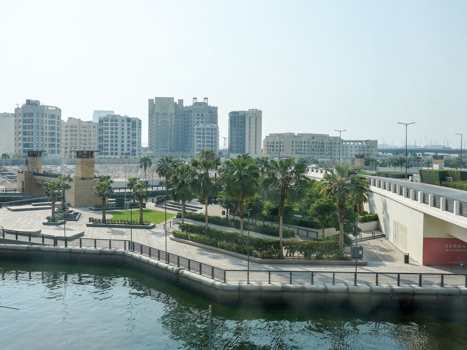 Jaddaf Waterfront skyline and a palm lined promenade beside an inlet of Dubai Creek in Al Jaddaf