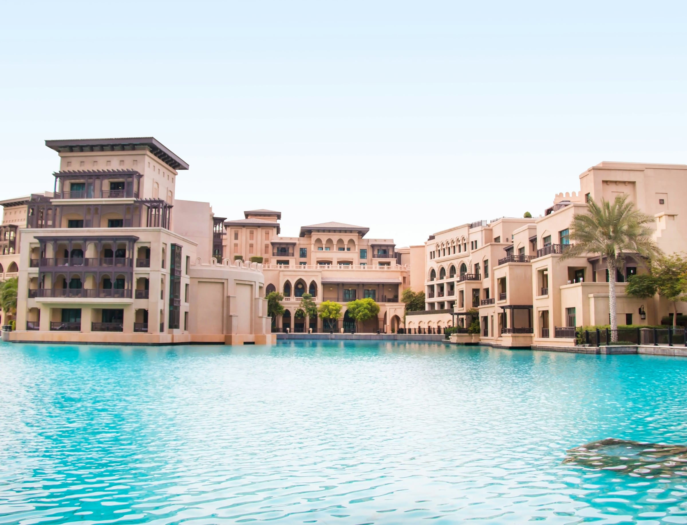 Mediterranean inspired architecture beside a turquoise lagoon pool in Dubai