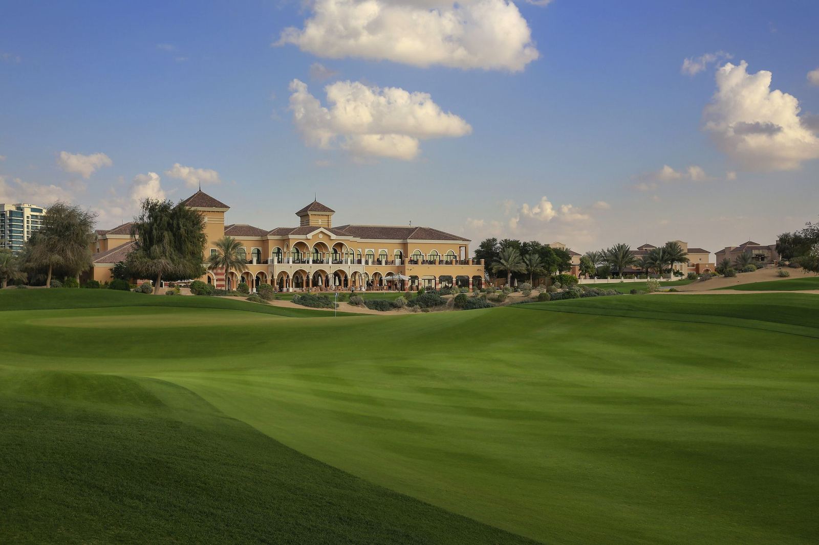 Green fairway of the Els Club golf course with its clubhouse in Dubai Sports City