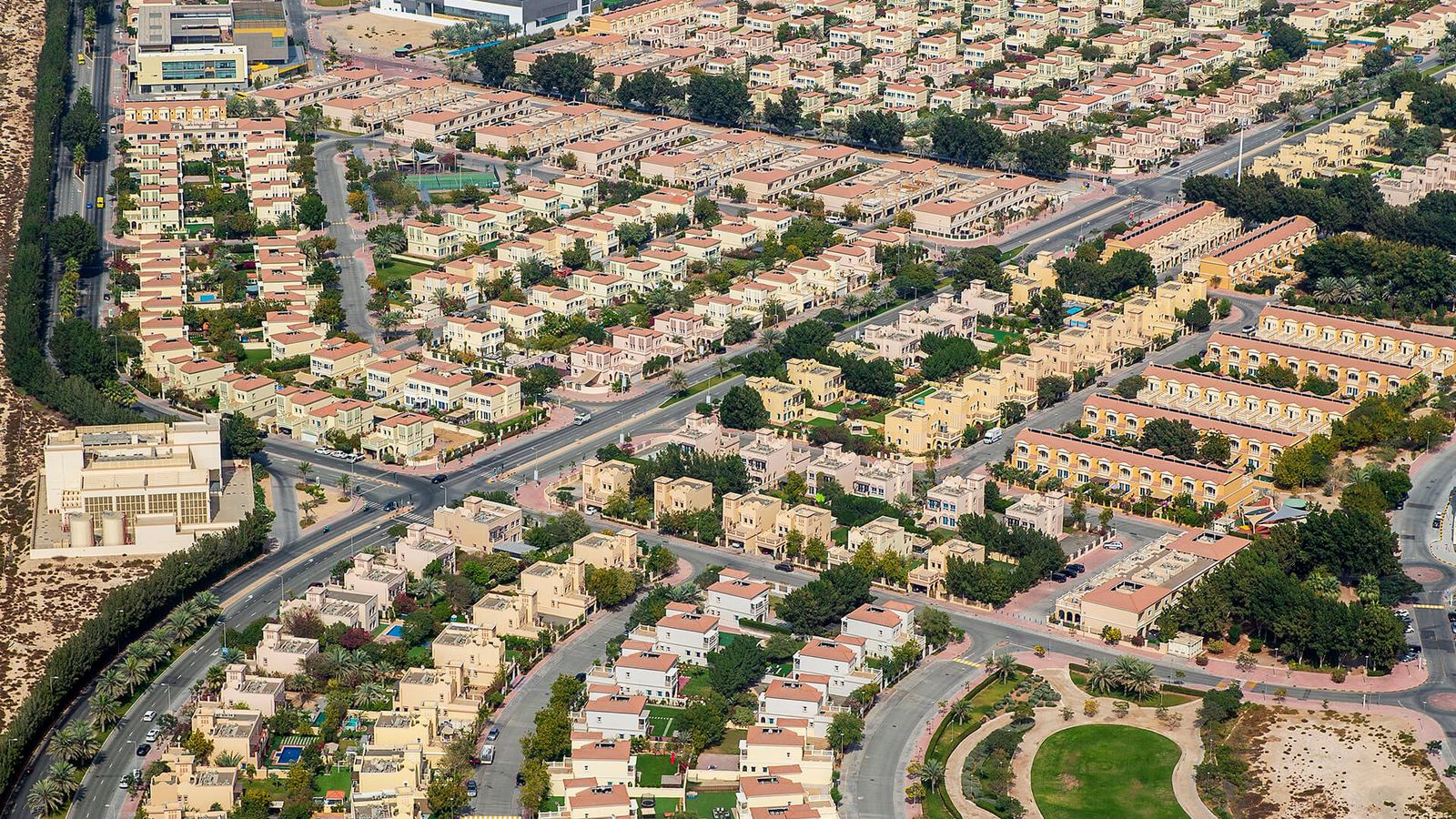Aerial view of Jumeirah Village Triangle villas, tree lined streets and a landscaped park