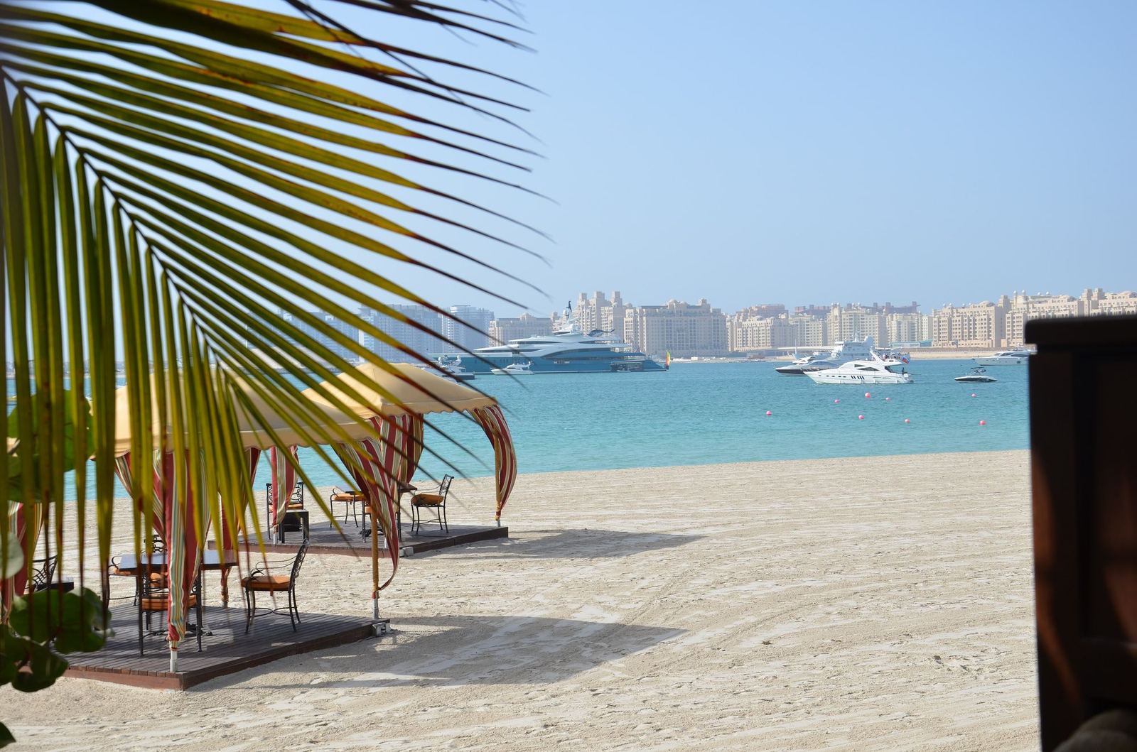 Sandy Al Sufouh beach with a shaded seating area and a view across the water to Palm Jumeirah