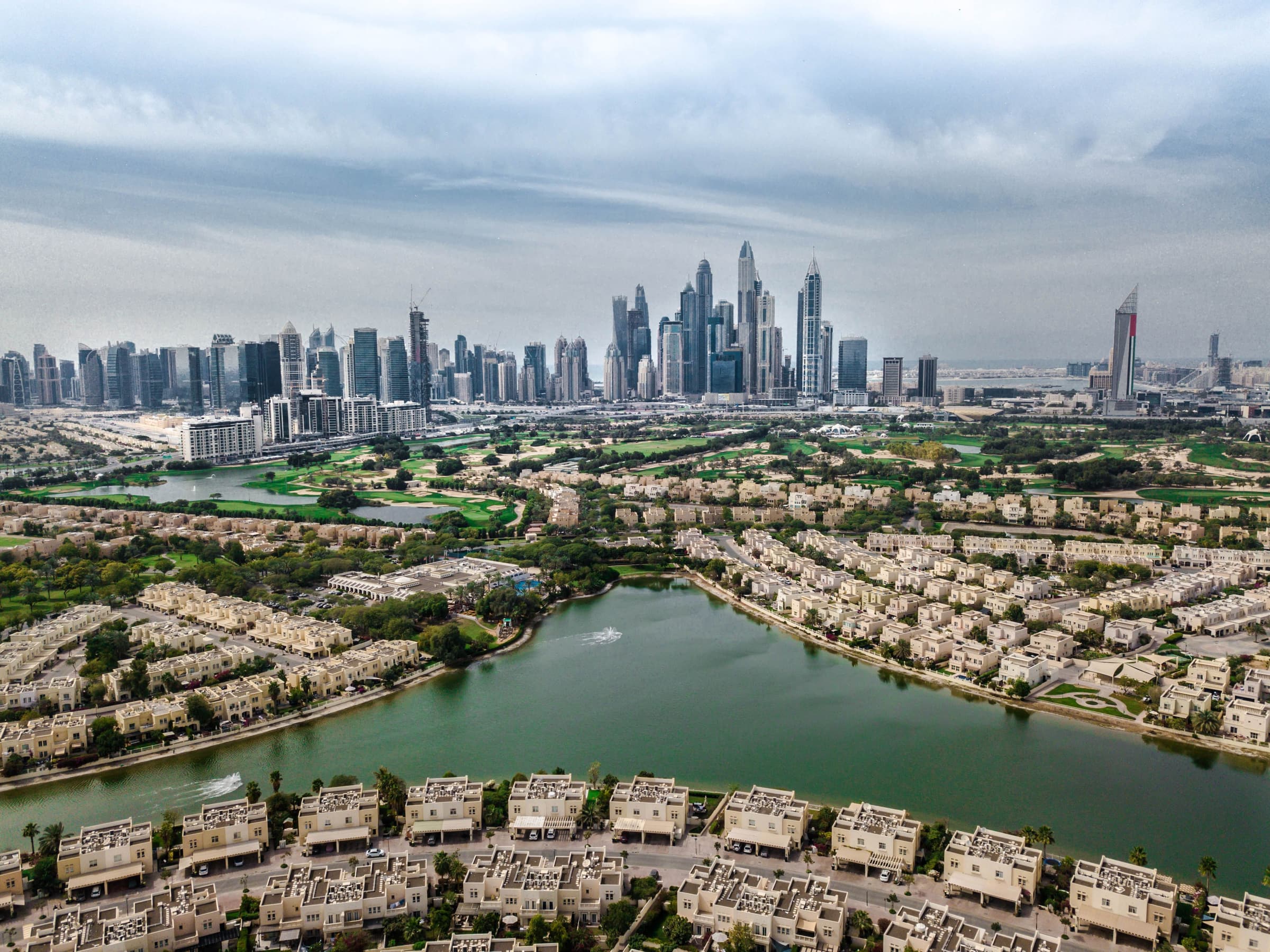 Townhouses of The Springs around a lake, with the JLT and Dubai Marina skyline beyond