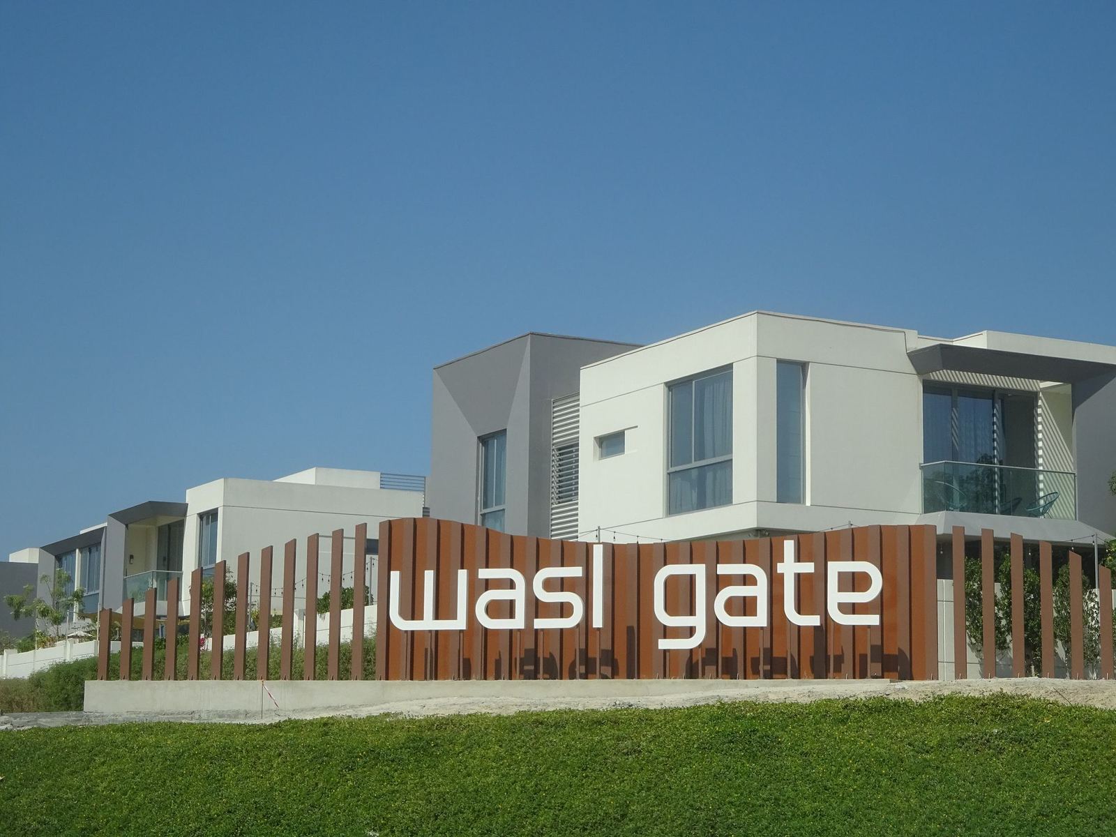 Modern villas behind the Wasl Gate community entrance sign in Jebel Ali, Dubai
